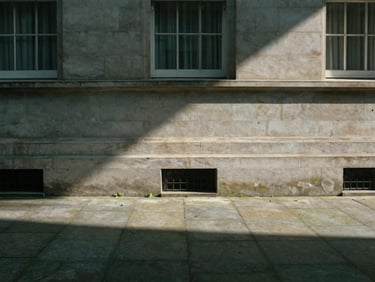 Subdued architectural detail of a private stone courtyard in London, soft afternoon shadows stretching across granite pavers, minimal and quiet, 35mm.
