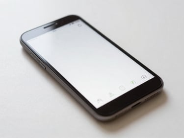 Macro 35mm photograph of a clean Android device displaying a minimalist, highly structured home screen layout with generous whitespace, soft side-lighting casting a gentle screen glow on a paper-white desk.