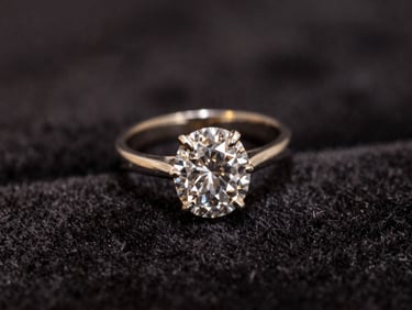 Macro shot of an antique diamond ring resting on dark velvet, soft golden highlights, shallow depth of field.