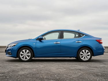 Full side view of a blue Nissan Sentra on a flat grey studio surface, natural overcast light, showing clean bodywork and factory wheels