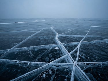 Cinematic wide-angle view of frozen ocean waves cracked with geometric precision, frosted textures, desaturated deep blue tones.
