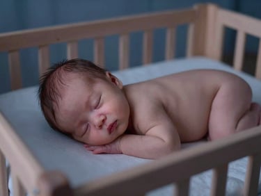 A peaceful newborn sleeping safely on their back in a wooden crib, soft twilight lamp light, muted indigo tones, shallow depth of field, 35mm