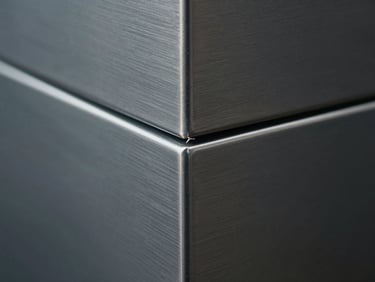 Extreme close-up of brushed steel panels joined by a razor-thin silver seam, cool-toned low-key lighting.