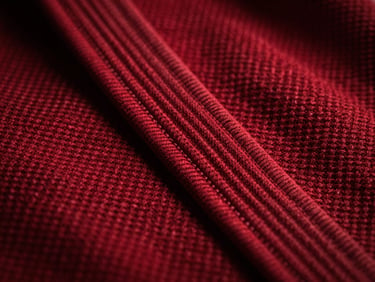 Macro shot of pearl weave cotton fabric on a BJJ uniform, showing texture and double-stitching, dramatic lighting.