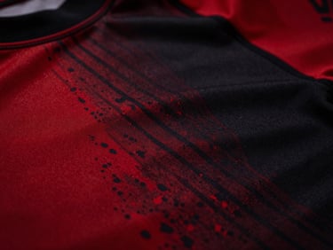 Extreme close-up of a rash guard fabric with visible flatlock stitching and vibrant dye sublimation pattern, high-contrast, deep red and black tones.