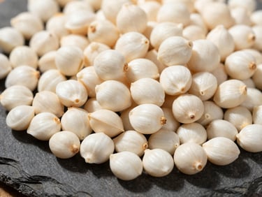 High-contrast macro shot of raw, white makhana seeds piled on a dark stone surface under bright sunlight, sharp textures.