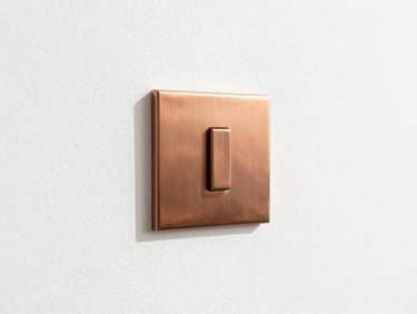 Detail of a minimalist copper switchplate flush-mounted on pristine white plaster, crisp architectural shadows, 35mm.