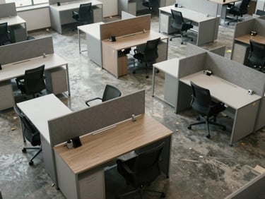 Overhead study of a corporate interior layout in progress, workstation surfaces and partition panels arranged on a polished concrete floor, natural light