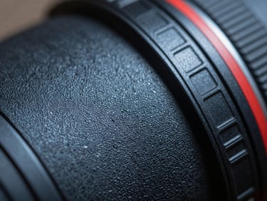 Macro close-up of a camera lens catching the texture of a painted surface sample, cool north light, shallow depth of field on material grain