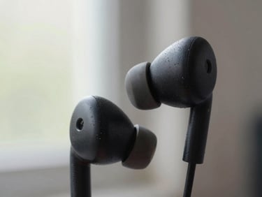 Close-up de um fone de ouvido sem fio, com marcas de suor visíveis, em um ambiente de academia com luz natural. Foco na textura do material e no uso real.