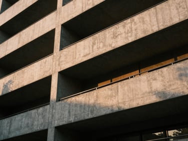 Abstract architectural close-up of a modern concrete building in Hyderabad, sharp geometric lines, soft golden hour light casting deep shadows, 35mm film.