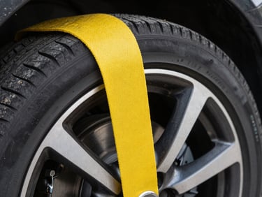 Extreme close-up of a heavy-duty yellow soft wheel strap wrapped securely around a clean sports car tire, showing zero contact with the alloy rim.