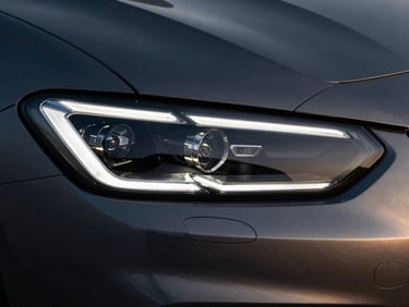 Extreme close-up of a modern sports car headlight, sharp geometric LED elements, cold metallic silver reflections, dark studio lighting, 35mm lens.