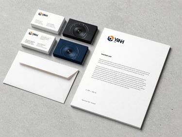 Flat lay of a brand identity system — business cards, envelope, and letterhead on a light concrete surface, neutral studio light, crisp printed edges