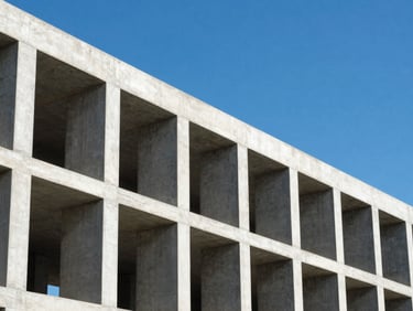 Modern concrete building skeleton with geometric columns under a bright blue sky, architectural lines, high contrast
