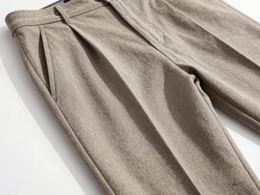 Editorial close-up of premium wool trousers drape, soft daylight casting shadows, highlighting the fine weave and elegant silhouette, neutral minimalist aesthetic, 85mm lens