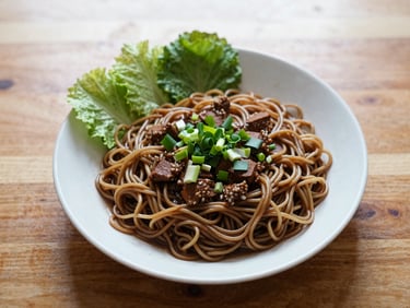 An overhead flatlay of a comforting local Malaysian noodle dish next to a western-style plate on a wooden table