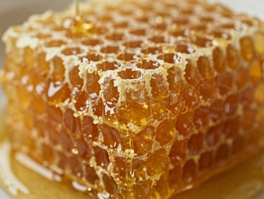 Close-up of raw, golden honeycomb dripping with fresh honey, soft natural light highlighting its texture, rich amber tones, shallow depth of field, 35mm.