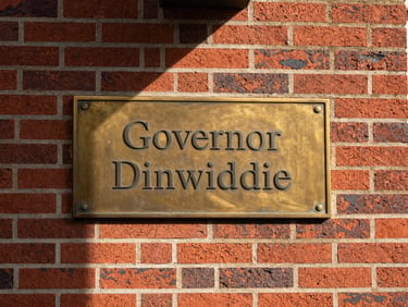 Close-up architectural detail of historic red brickwork and polished brass plaque reading Governor Dinwiddie, soft morning shadows, stately corporate aesthetic, 35mm