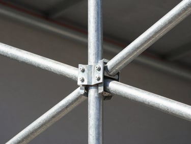 Close-up of a galvanized steel scaffold joint with cross bracing for construction support.