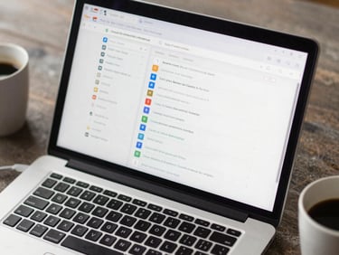 Overhead shot of a laptop open to a Google Ads campaign structure view, ad groups and match types visible, a coffee cup in the corner of frame, soft overcast daylight