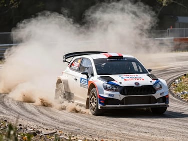 Dynamic motorsport photography, rally car accelerating on asphalt, dramatic dust trail, high-contrast daylight, wide shot, sharp action focus