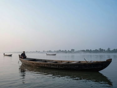 Cinematic wide shot of traditional wooden boats on a wide river in Bangladesh, misty morning light, soft atmospheric glow.