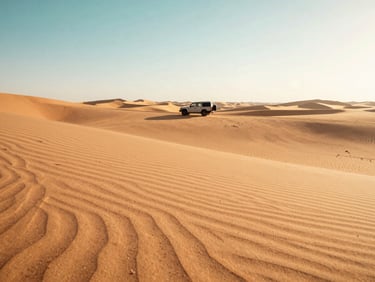 An empty, vast desert dune landscape at golden hour, with a luxury 4x4 vehicle parked in the distance, casting long shadows. Warm sand tones, 35mm.