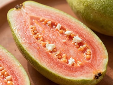 Close-up of a cheese and guava paleta showing pink guava pulp and white cheese flecks.