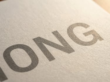 Close-up macro shot of textured heavy-weight paper packaging with minimalist slate gray typography, soft golden-hour light highlighting the grain.
