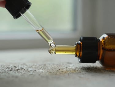 Macro close-up of an amber glass dropper bottle resting on a rustic stone surface, soft natural window light, muted sage green background, 35mm