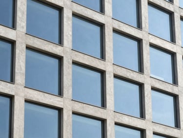 Crisp architectural detail of a modern concrete and glass office building facade, reflecting bright blue sky, clean geometric lines, sharp focus