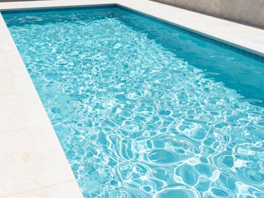 Wide shot of a newly installed linear swimming pool with sparkling clear water, modern patio, bright natural daylight, crisp architectural photography.