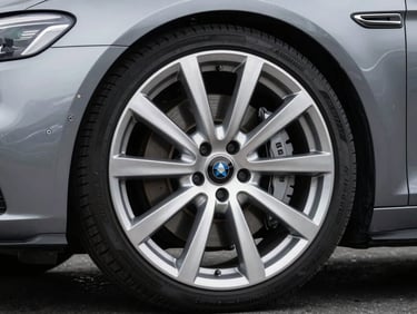 Macro shot of a polished executive sedan wheel and chrome front grille, sharp studio lighting highlighting the pristine metallic details