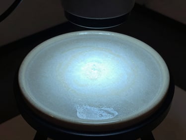 Macro photograph of cured ceramic coating surface under UV inspection lamp in a dark studio environment, the cured layer glowing with a faint blue tint showing complete and even coverage