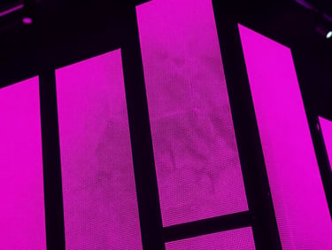 Close-up of high-definition modular LED screen panels showing intense contrast and vibrant magenta test patterns, sharp technical details, dark background.