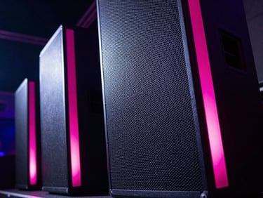 Vibrant close-up of high-end concert speakers in a dark venue, glowing pink led accents on the edges, sharp details