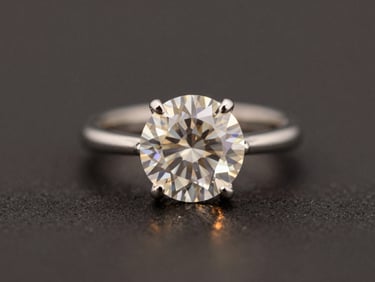 Macro shot of a brilliant-cut diamond ring, facets catching warm side-light, set in a platinum band, deep charcoal background, elegant.