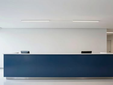 Minimalist architectural photography of a modern clinical reception lobby, clean lines, soft overcast light, deep blue accents, 35mm