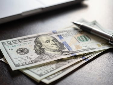 Tight macro shot of financial notes and a pen on a dark desk, directional window light.