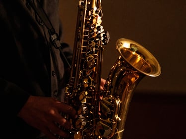 Close-up of a brass saxophone catching warm amber candlelight, deep shadows, high-contrast chiaroscuro, 35mm film grain