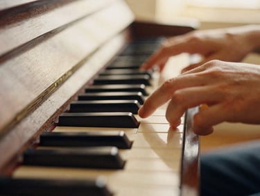 Close-up of fingers pressing piano keys, warm wood texture, soft side-lighting, 35mm film