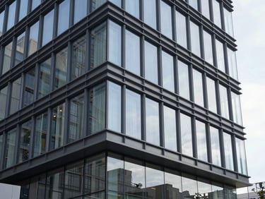 Sleek modern commercial building exterior with glass facade and steel structure, clean architectural lines under crisp daylight.