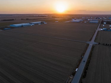High-resolution drone view of a clean, flat commercial land parcel near Tuşba, Van, sunset lighting, clear road access visible.