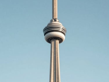 CN Tower in Toronto photographed frontally in bright even daylight, clean blue sky, architectural precision, no tourism warmth, calm institutional framing