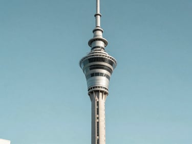 Sky Tower in Auckland photographed frontally in bright even daylight, clean sky, architectural precision, calm institutional framing, no tourism warmth