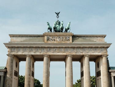Brandenburg Gate in Berlin photographed frontally in bright even daylight, clean sky, architectural precision, calm institutional light, no tourism warmth