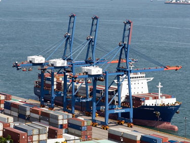 High-angle architectural shot of a massive deep-water shipping terminal in Hong Kong, towering blue container cranes, crisp daylight, slate gray tones.