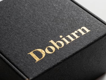 Close-up of heavy-weight textured black cardboard box with gold foil debossing, elegant packaging.