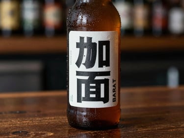 Close-up of a crisp, chilled amber bottle of craft beer with a bold typographic label, sitting on a dark wooden counter.